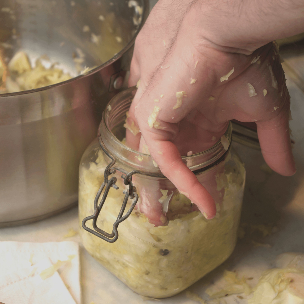 Start pressing the cabbage into the jar.